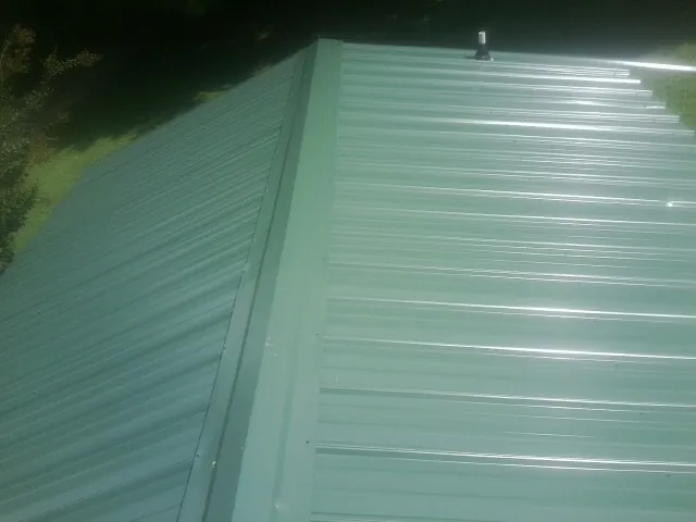 New green metal panels meeting at the ridge of a roof — Flat Roof Repair work by our crew in Gunlock