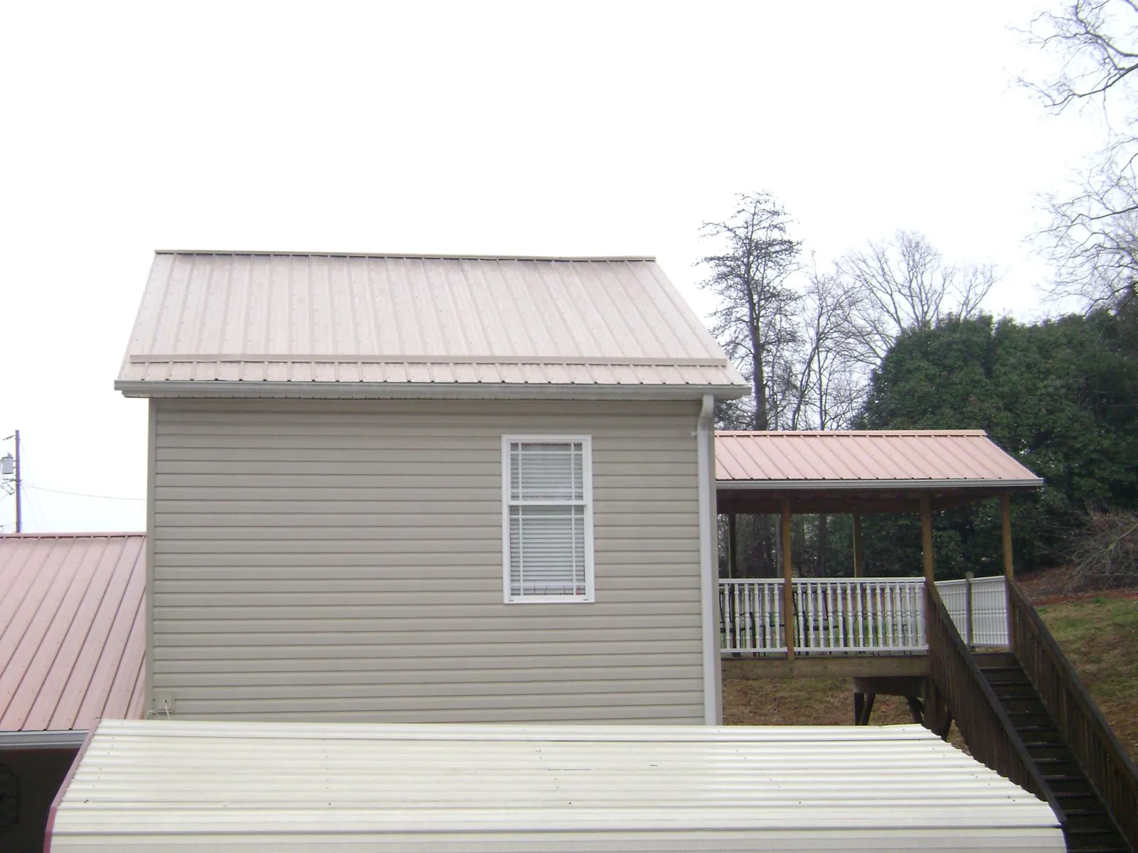 Tan metal roofs on a two story addition and attached porch, from a Roof Replacement job in Gunlock