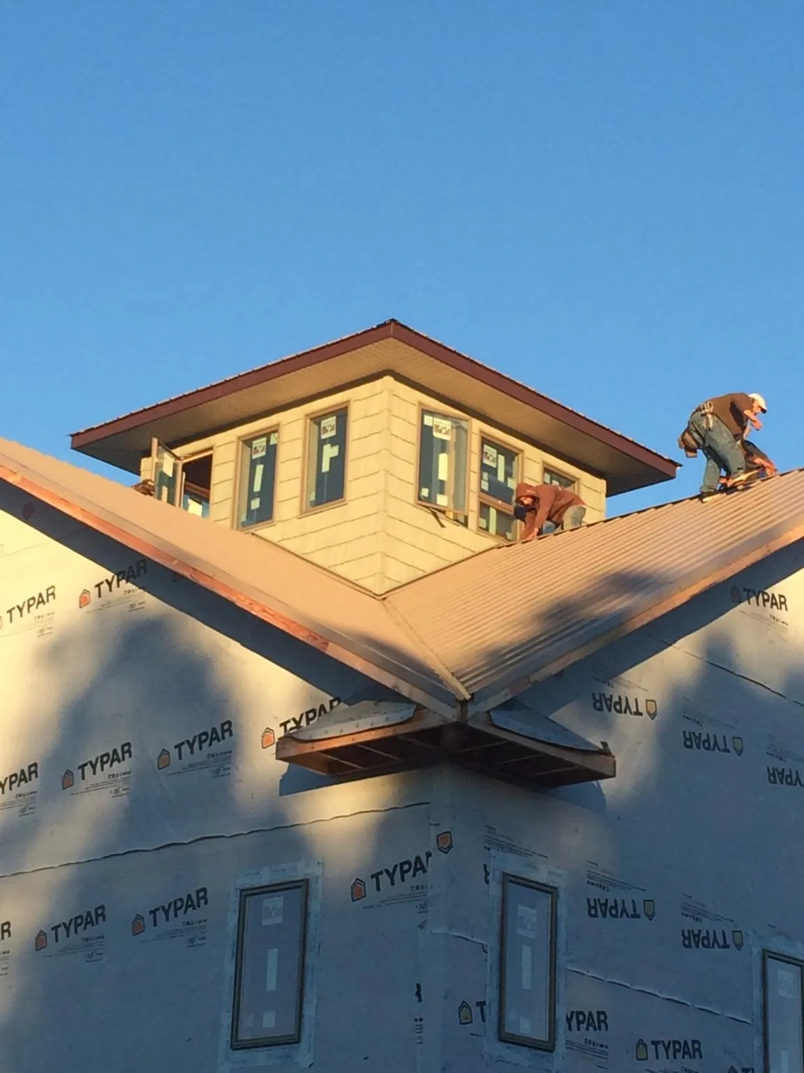 Roofers working around a rooftop cupola on a new metal roof at sunset — Roof Waterproofing in Gunlock by Roofing Brothers